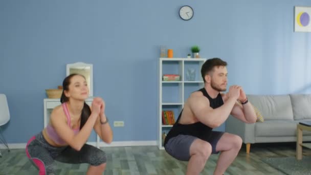 Junge Männer und Frauen machen synchrone Kniebeugen — Stockvideo