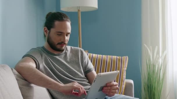 Ο άνθρωπος κάθεται στον καναπέ, χρησιμοποιώντας Gadget — Αρχείο Βίντεο