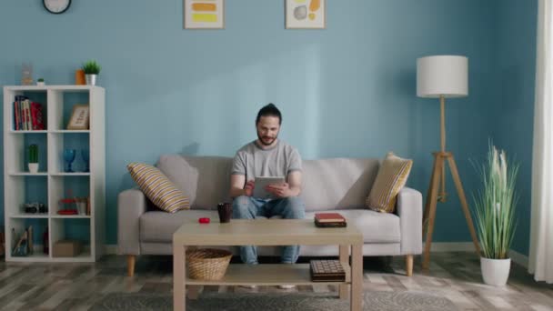 Ο άνθρωπος κάθεται στον καναπέ χρησιμοποιώντας Gadget για να μείνετε σε επαφή — Αρχείο Βίντεο