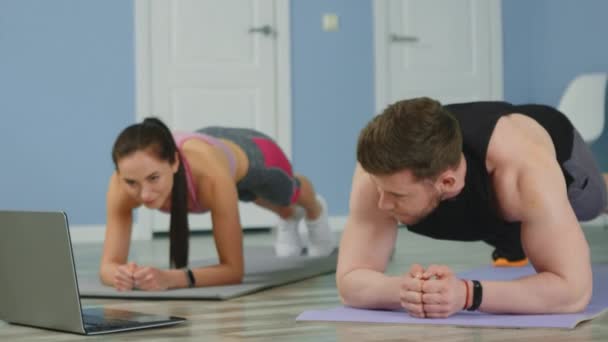 Pareja joven está haciendo ejercicios abdominales en casa — Vídeos de Stock