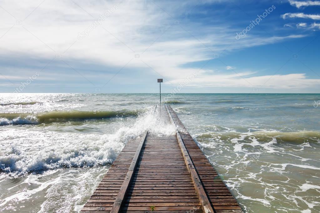 Pier and waves on the beach of Lido di Jesolo near Venice, Veneto region, Italy.