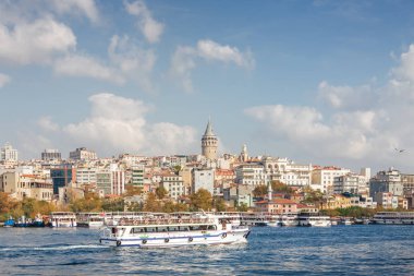 Boğaziçi'nin güneşli görünümüyle gezi tekneleri ve Galata Kulesi, Istanbul, Türkiye.