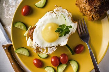 Sandviç kızarmış yumurta, salatalık ve domates ekmek ve süt keten masa örtüsü, karanlık ve huysuz tabak.