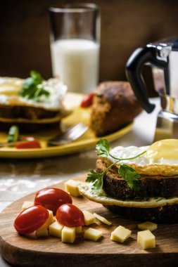 Sandviç kızarmış yumurta, salatalık ve domates ekmek ve süt keten masa örtüsü, karanlık ve huysuz tabak.