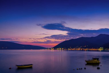 Karadağ 'ın Tivat kenti yakınlarındaki Kotor körfezi ve kıyı yolunun gün batımı manzarası
