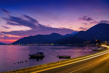 Karadağ 'ın Tivat kenti yakınlarındaki Kotor körfezi ve kıyı yolunun gün batımı manzarası