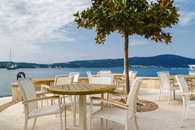 Beautiful and cozy street cafe on the background of luxury yacht