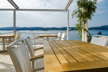 Beautiful and cozy street cafe on the background of luxury yacht