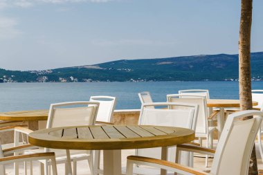 Beautiful and cozy street cafe on the background of luxury yacht
