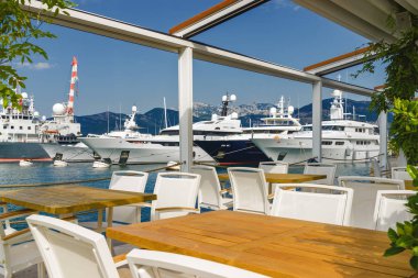 Beautiful and cozy street cafe on the background of luxury yacht