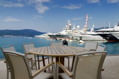 Beautiful and cozy street cafe on the background of luxury yacht