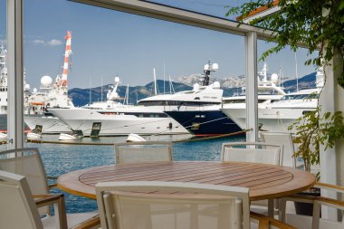 Beautiful and cozy street cafe on the background of luxury yacht
