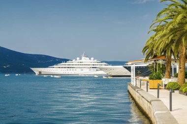 Beautiful and cozy street cafe on the background of luxury yacht
