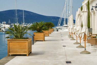 Beautiful and cozy street cafe on the background of luxury yacht