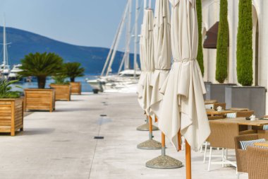 Beautiful and cozy street cafe on the background of luxury yacht