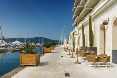 Beautiful and cozy street cafe on the background of luxury yacht