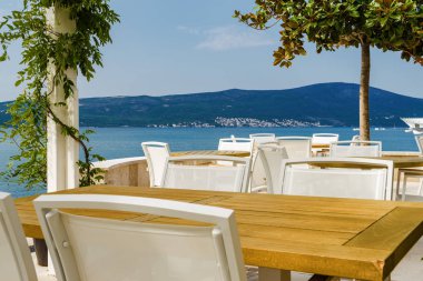 Beautiful and cozy street cafe on the background of luxury yacht