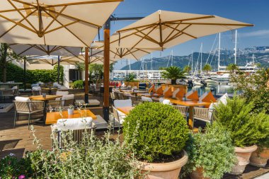 Beautiful and cozy street cafe on the background of luxury yacht