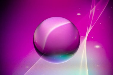 Kristal cam küre renkli soyut arka planda taş bir yüzeyde yatıyor.. 