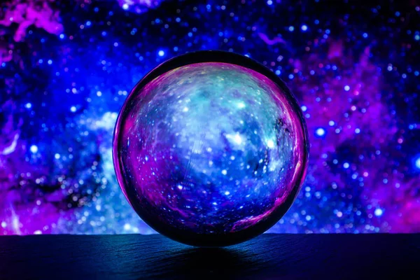 Kristal cam küre renkli soyut arka planda taş bir yüzeyde yatıyor.. 