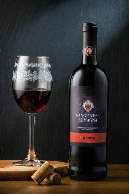 MOSCOW, RUSSIA - ŞUBAT 05, 2019: Bir şişe kuru kırmızı İtalyan şarabı Sangiovese Romagnia ve siyah taş arka planda bir şarap bardağını doldurdu.