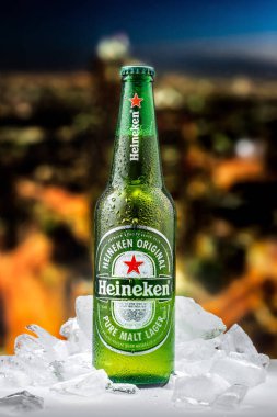 MOSCOW, RUSSIA - 26 Nisan 2020: Bir şişe Heineken birası ve New York şehir merkezindeki günbatımının arka planında buz parçaları. Bu Heineken International 'ın amiral gemisi..