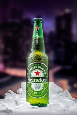 MOSCOW, RUSSIA - 26 Nisan 2020: Bir şişe Heineken birası ve New York şehir merkezindeki günbatımının arka planında buz parçaları. Bu Heineken International 'ın amiral gemisi..