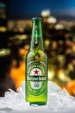 MOSCOW, RUSSIA - 26 Nisan 2020: Bir şişe Heineken birası ve New York şehir merkezindeki günbatımının arka planında buz parçaları. Bu Heineken International 'ın amiral gemisi..