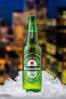 MOSCOW, RUSSIA - 26 Nisan 2020: Bir şişe Heineken birası ve New York şehir merkezindeki günbatımının arka planında buz parçaları. Bu Heineken International 'ın amiral gemisi..