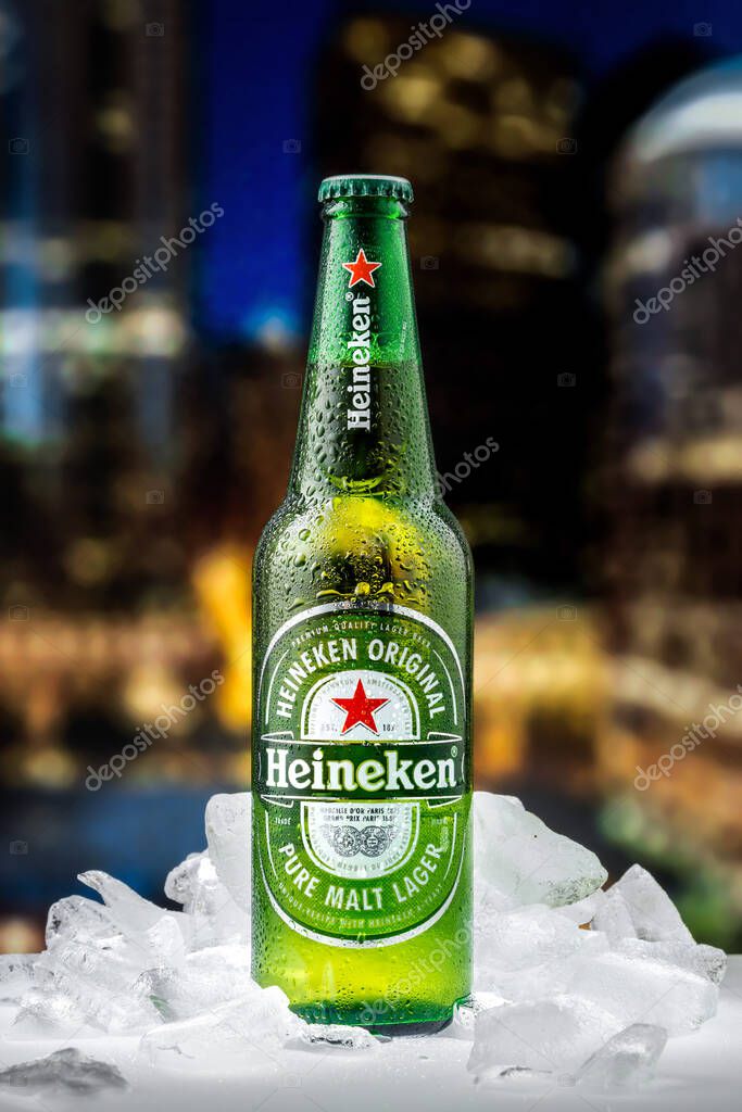 MOSCOW, RUSSIA - APRIL 26, 2020: Bottle of Heineken lager beer with pieces of ice on the background of sunset downtown of New York. This is flagship product of Heineken International.