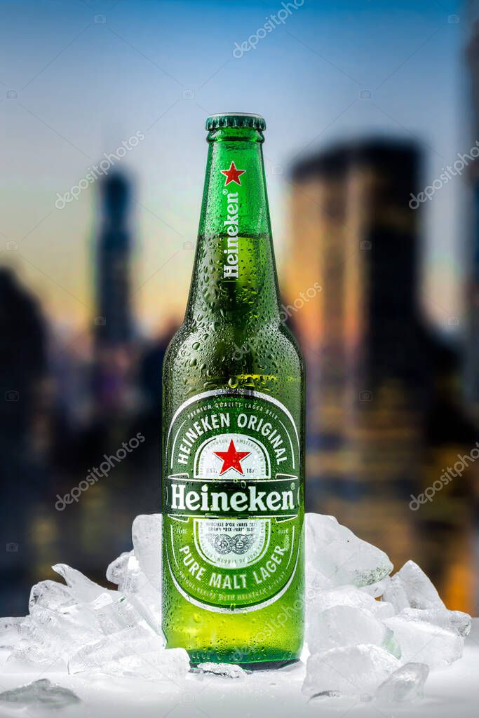 MOSCOW, RUSSIA - APRIL 26, 2020: Bottle of Heineken lager beer with pieces of ice on the background of sunset downtown of New York. This is flagship product of Heineken International.