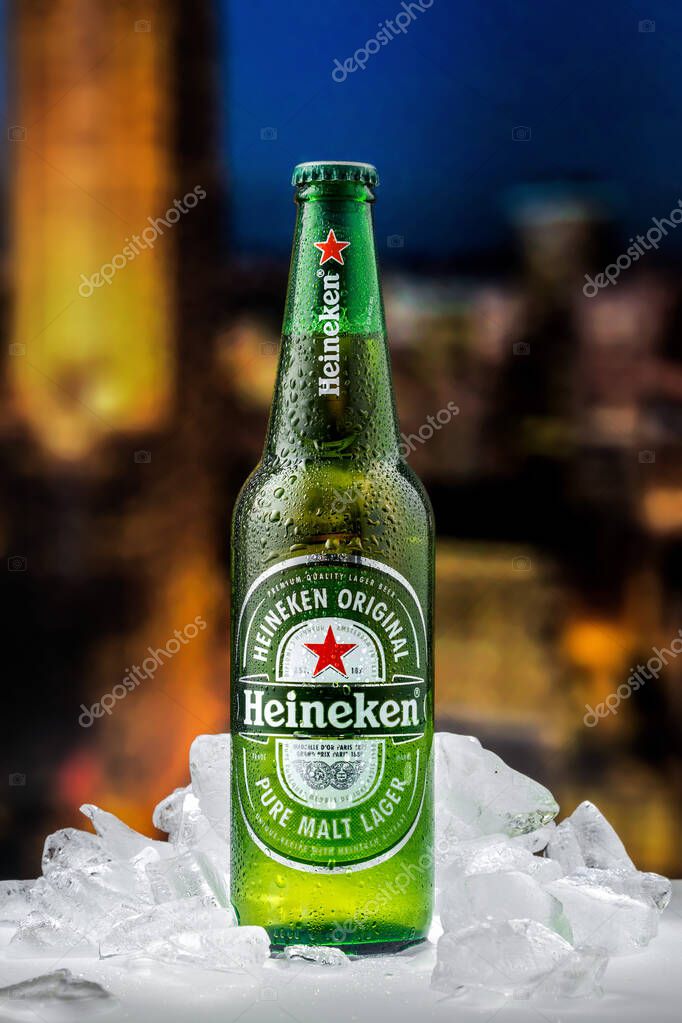 MOSCOW, RUSSIA - APRIL 26, 2020: Bottle of Heineken lager beer with pieces of ice on the background of sunset downtown of New York. This is flagship product of Heineken International.