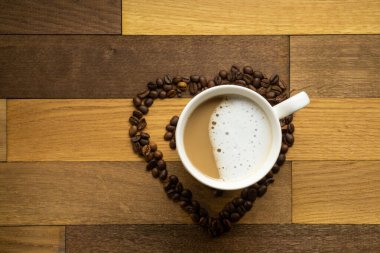 Kahve çekirdekleri ve kahve fincanının bileşimi. Tahta tuğlalar üzerinde süt, düz görünüm..