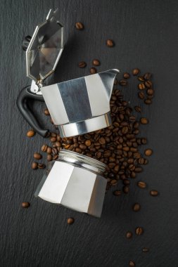 Kahve çekirdekleri ve kahve makinesi kompozisyonu siyah taş arka planda, düz görünüm.