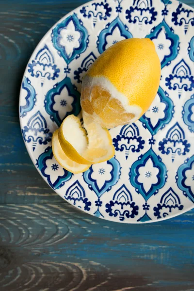 Amarillo limón fresco en el plato con patrón azul sobre fondo de madera —  Fotos de Stock