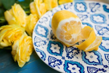 Ahşap zemin üzerine mavi desenli plaka üzerinde sarı taze limon