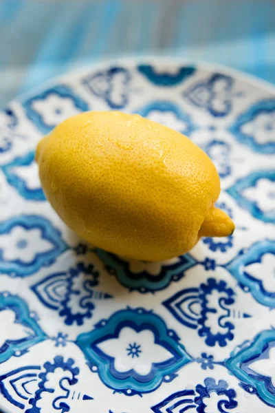 Lemon kuning segar di piring dengan pola biru pada latar belakang kayu — Stok Foto