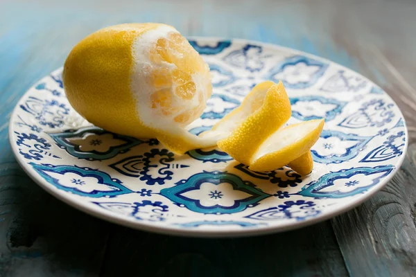 Желтый свежий лимон на тарелке с голубым узором на деревянном фоне — стоковое фото