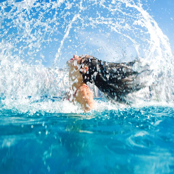 Spruzzi d'acqua dai capelli della ragazza in piscina — Foto Stock