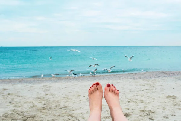 Pieds de femme avec des ongles rouges sur le fond de la mer — Photo