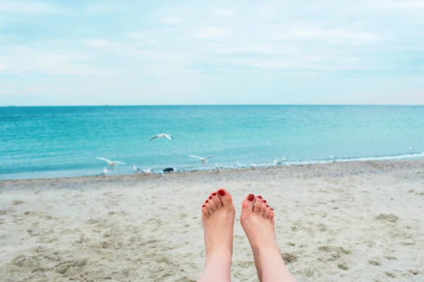 Pieds de femme avec des ongles rouges sur le fond de la mer — Photo