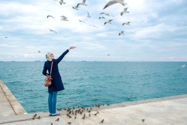 sarışın kadın martılar bulutlu sonbahar günü deniz kıyısında besleme. 