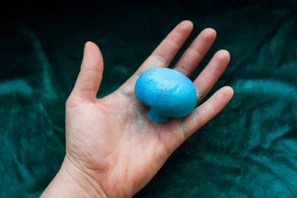 Fantastischer blauer Pilz in der Hand auf grünem Samthintergrund — Stockfoto
