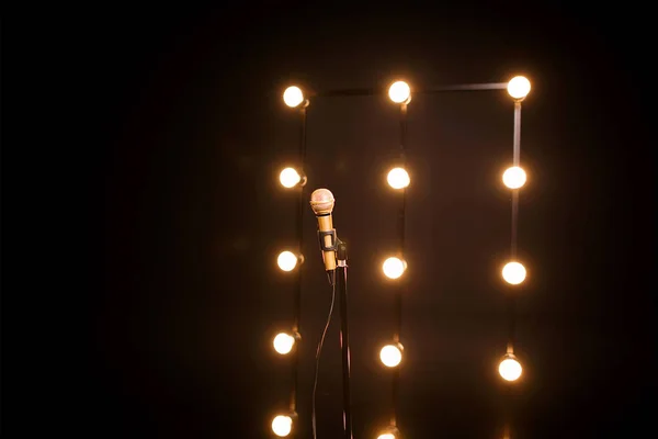 gold microphone on microphone stand on dark background with many lights