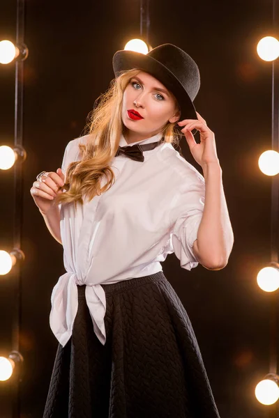 Joven rubia atractiva mujer en camisa blanca, mariposa, sombrero negro sobre fondo oscuro —  Fotos de Stock