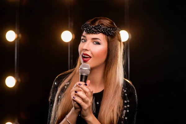 Νέοι smiley όμορφα μακριά μαλλιά κορίτσι με μαύρο φόρεμα με μικρόφωνο τραγουδώντας το τραγούδι στη σκηνή σε καραόκε — Φωτογραφία Αρχείου