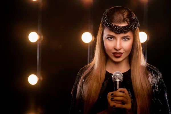 Νέοι smiley όμορφα μακριά μαλλιά κορίτσι με μαύρο φόρεμα με μικρόφωνο τραγουδώντας το τραγούδι στη σκηνή σε καραόκε — Φωτογραφία Αρχείου