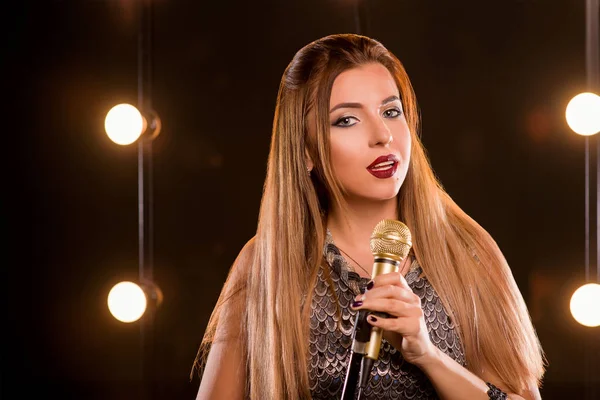 Mladý obličej krásné dlouhé vlasy dívka s zpěvu písní na jevišti v karaoke mikrofon — Stock fotografie