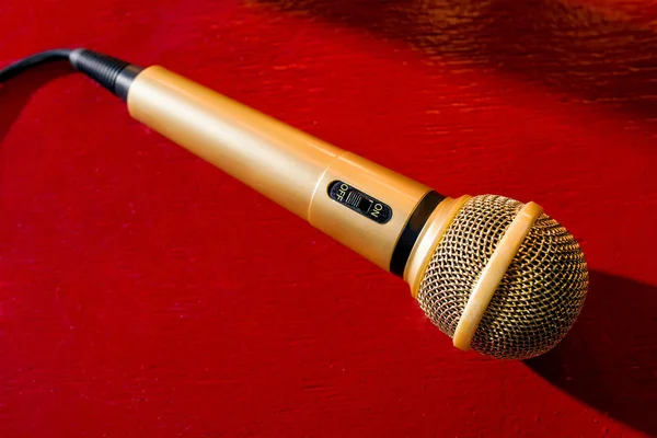gold microphone on red wooden and dark background with many lights