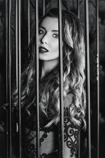 Jonge mooie aantrekkelijk en warm lange haren vrouw in zwarte ondergoed in de kooi in de fotostudio — Stockfoto